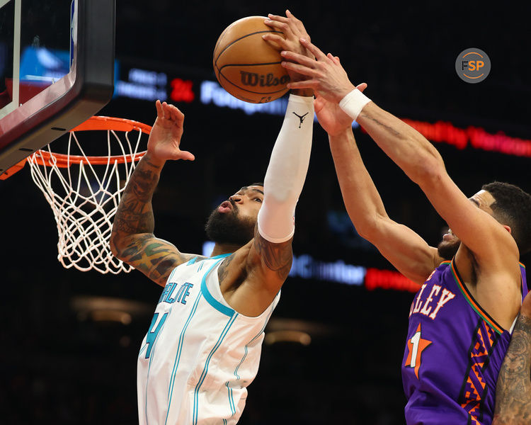 Jan 12, 2025; Phoenix, Arizona, USA; Charlotte Hornets center Nick Richards (4) shoots the ball past Phoenix Suns guard Devin Booker (1) during the second half at Footprint Center. Credit: Mark J. Rebilas-Imagn Images