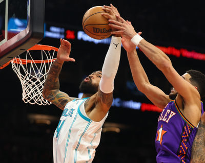 Jan 12, 2025; Phoenix, Arizona, USA; Charlotte Hornets center Nick Richards (4) shoots the ball past Phoenix Suns guard Devin Booker (1) during the second half at Footprint Center. Mandatory Credit: Mark J. Rebilas-Imagn Images