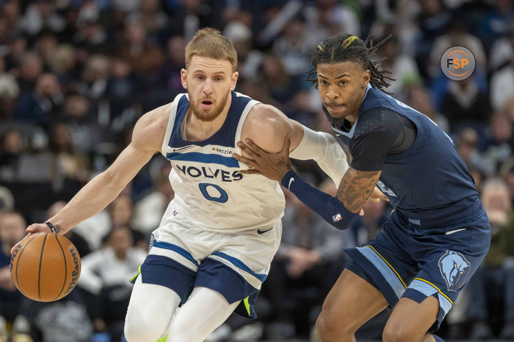 Jan 11, 2025; Minneapolis, Minnesota, USA; Minnesota Timberwolves guard Donte DiVincenzo (0) dribbles the ball against Memphis Grizzlies guard Ja Morant (12) in the first half at Target Center. Credit: Jesse Johnson-Imagn Images