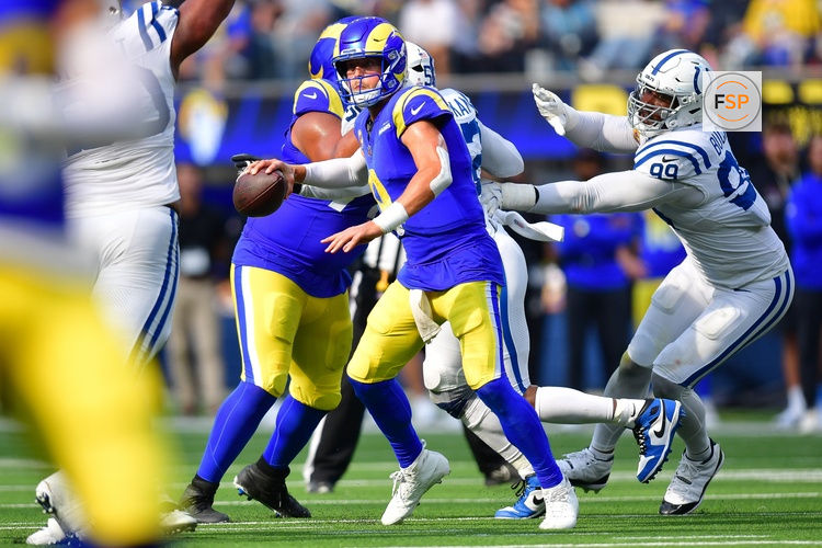 Sep 28, 2025; Inglewood, California, USA; Los Angeles Rams quarterback Matthew Stafford (9) runs out to pass as Indianapolis Colts defensive tackle Deforest Buckner (99) moves in during the second half at SoFi Stadium. Credit: Gary A. Vasquez-Imagn Images