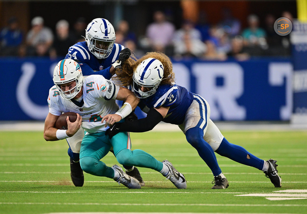 Oct 20, 2024; Indianapolis, Indiana, USA; Miami Dolphins quarterback Tim Boyle (14) is tackled by Indianapolis Colts defensive end Dayo Odeyingbo (54) and linebacker Grant Stuard (41) during the second half at Lucas Oil Stadium. Credit: Marc Lebryk-Imagn Images