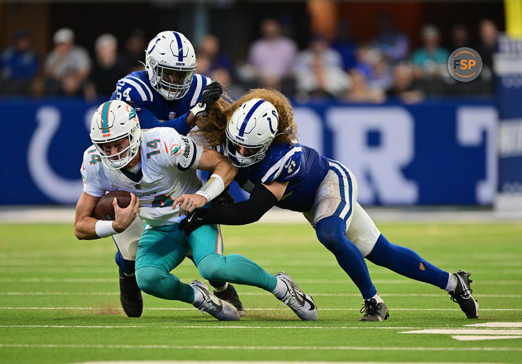 Oct 20, 2024; Indianapolis, Indiana, USA; Miami Dolphins quarterback Tim Boyle (14) is tackled by Indianapolis Colts defensive end Dayo Odeyingbo (54) and linebacker Grant Stuard (41) during the second half at Lucas Oil Stadium. Credit: Marc Lebryk-Imagn Images