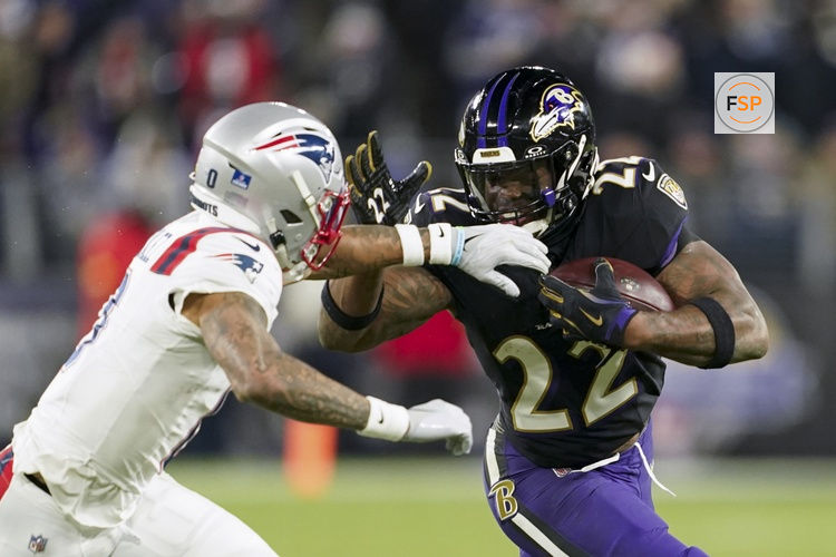 Dec 21, 2025; Baltimore, Maryland, USA;  Baltimore Ravens running back Derrick Henry (22) runs the ball against New England Patriots cornerback Christian Gonzalez (0) during the second half of the game at M&T Bank Stadium. Credit: Mitch Stringer-Imagn Images