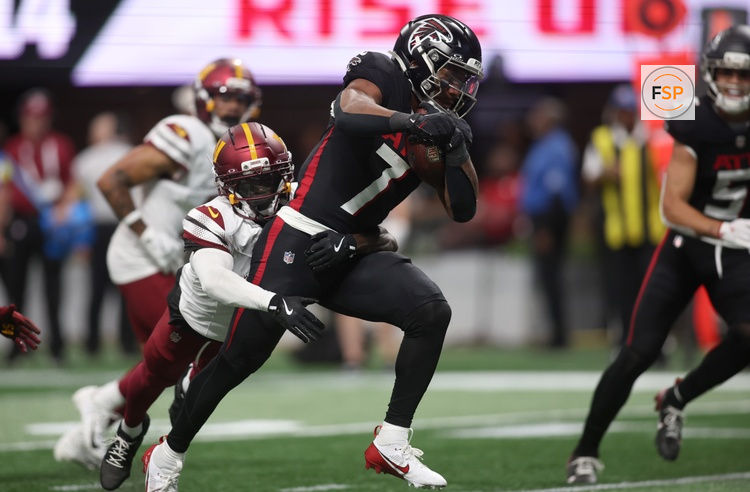 Sep 28, 2025; Atlanta, Georgia, USA; Atlanta Falcons running back Bijan Robinson (7) scores a touchdown against Washington Commanders cornerback Mike Sainristil (0) during the first half at Mercedes-Benz Stadium. Credit: Brett Davis-Imagn Images