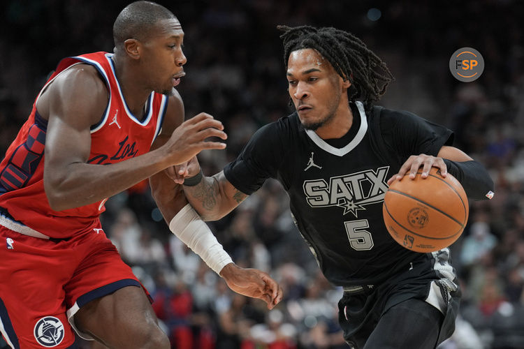 Dec 31, 2024; San Antonio, Texas, USA;  San Antonio Spurs guard Stephon Castle (5) dribbles against LA Clippers guard Kris Dunn (8) in the second half at Frost Bank Center. Credit: Daniel Dunn-Imagn Images