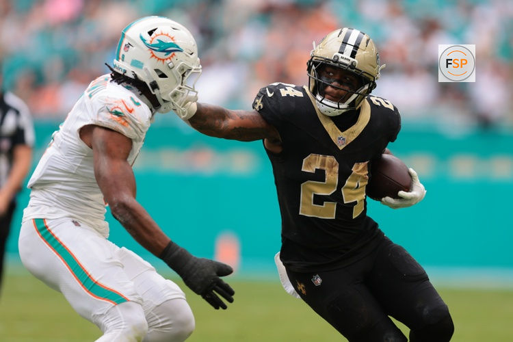 Nov 30, 2025; Miami Gardens, Florida, USA; New Orleans Saints running back Devin Neal (24) carries the ball as Miami Dolphins linebacker K.J. Britt (3) defends during the second half at Hard Rock Stadium. Credit: Sam Navarro-Imagn Images