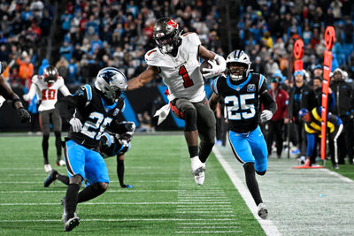 Dec 1, 2024; Charlotte, North Carolina, USA; Tampa Bay Buccaneers running back Rachaad White (1) runs the ball into the red zone as Carolina Panthers cornerback Chau Smith-Wade (26) and safety Xavier Woods (25) defend in overtime at Bank of America Stadium. Mandatory Credit: Bob Donnan-Imagn Images