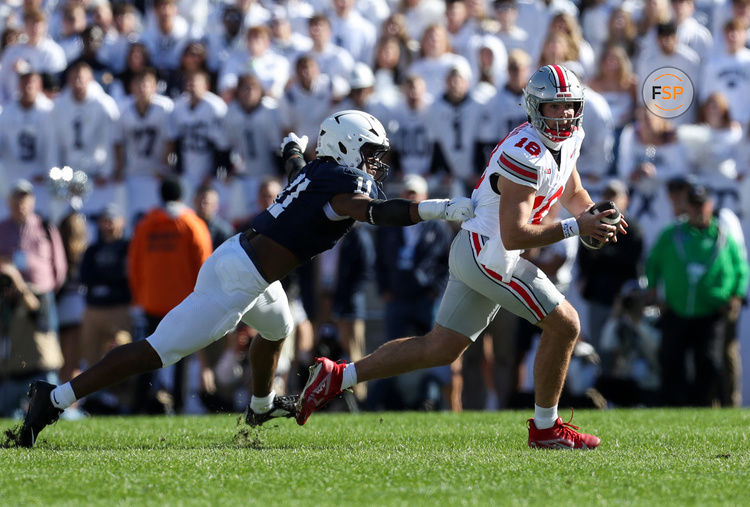 Nov 2, 2024; University Park, Pennsylvania, USA; Ohio State Buckeyes quarterback Will Howard (18) runs with the ball while being pressured by Penn State Nittany Lions defensive end Abdul Carter (11) during the second quarter at Beaver Stadium. Credit: Matthew O'Haren-Imagn Images