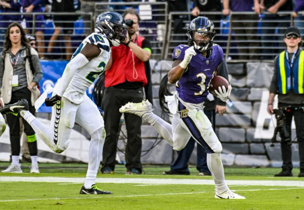 BALTIMORE, MD - NOVEMBER 05: Baltimore Ravens running back Keaton Mitchell (34) runs for a touchdown against Seattle Seahawks cornerback Riq Woolen (27) during the Seattle Seahawks game versus the Baltimore Ravens on November 5, 2023 at M&T Bank Stadium in Baltimore, MD. (Photo by Mark Goldman/Icon Sportswire)
