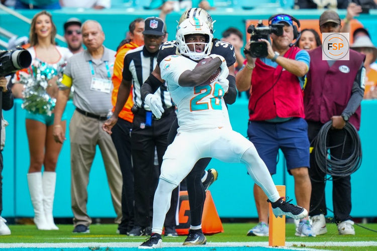 Nov 30, 2025; Miami Gardens, Florida, USA; Miami Dolphins running back De'Von Achane (28) scores a touchdown as New Orleans Saints safety Jordan Howden (31) defends during the first half at Hard Rock Stadium. Credit: Rich Storry-Imagn Images
