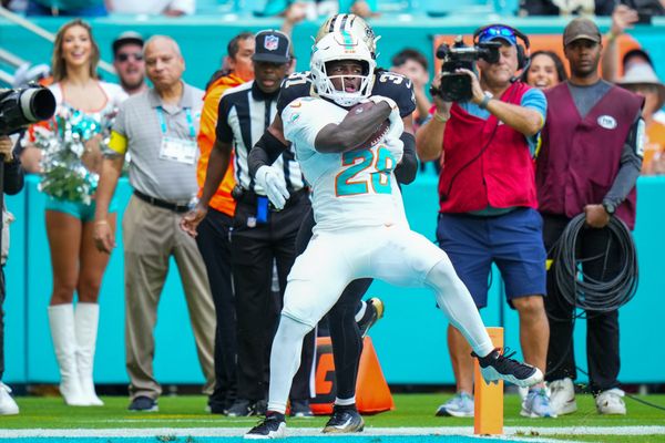 Nov 30, 2025; Miami Gardens, Florida, USA; Miami Dolphins running back De'Von Achane (28) scores a touchdown as New Orleans Saints safety Jordan Howden (31) defends during the first half at Hard Rock Stadium. Mandatory Credit: Rich Storry-Imagn Images