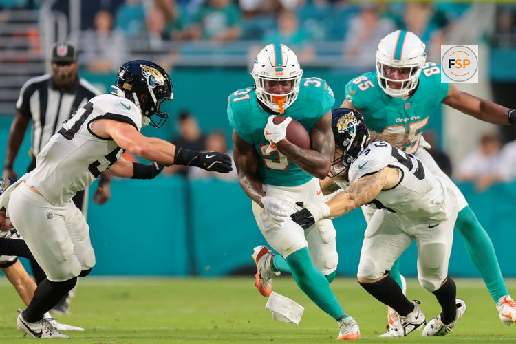 Aug 23, 2025; Miami Gardens, Florida, USA; Miami Dolphins running back Ollie Gordon II (31) runs with the football past Jacksonville Jaguars linebacker Dennis Gardeck (57) and linebacker Branson Combs (50) during the second quarter at Hard Rock Stadium. Credit: Sam Navarro-Imagn Images