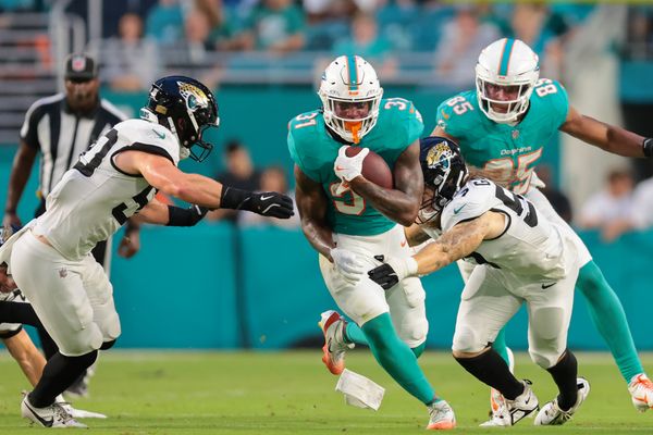 Aug 23, 2025; Miami Gardens, Florida, USA; Miami Dolphins running back Ollie Gordon II (31) runs with the football past Jacksonville Jaguars linebacker Dennis Gardeck (57) and linebacker Branson Combs (50) during the second quarter at Hard Rock Stadium. Mandatory Credit: Sam Navarro-Imagn Images