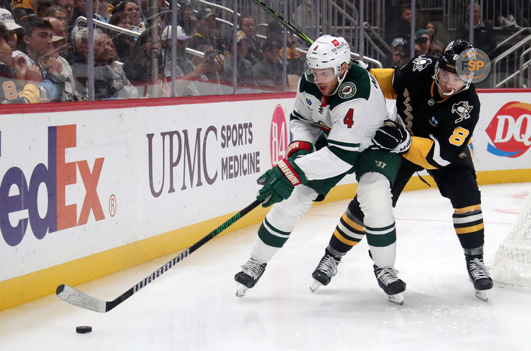 Oct 29, 2024; Pittsburgh, Pennsylvania, USA;  Minnesota Wild defenseman Jon Merrill (4) chases the puck against pressure from Pittsburgh Penguins left wing Michael Bunting (8) during the second period at PPG Paints Arena. Credit: Charles LeClaire-Imagn Images