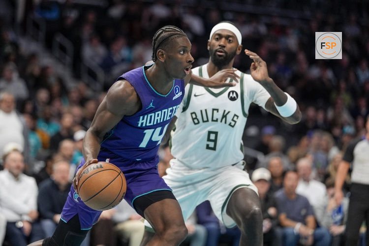 Nov 12, 2025; Charlotte, North Carolina, USA; Charlotte Hornets forward Moussa Diabate (14) looks to pass defended by Milwaukee Bucks forward Bobby Portis (9) during the first quarter at Spectrum Center. Credit: Jim Dedmon-Imagn Images