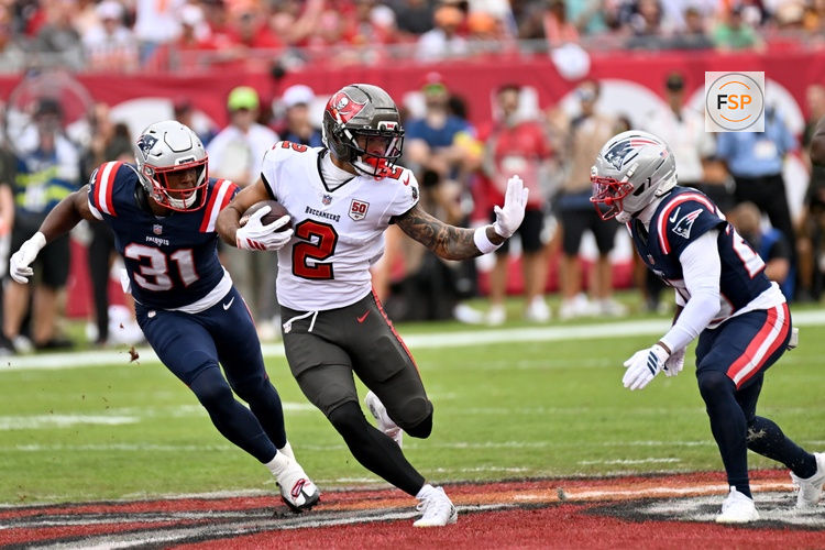 Nov 9, 2025; Tampa, Florida, USA; Tampa Bay Buccaneers wide receiver Emeka Egbuka (2) runs for a gain past New England Patriots safety Craig Woodson (31) and cornerback Marcus Jones (25) during the first quarter at Raymond James Stadium. Credit: Jonathan Dyer-Imagn Images