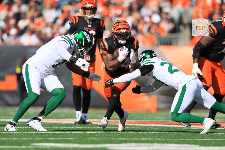 Oct 26, 2025; Cincinnati, Ohio, USA; Cincinnati Bengals running back Samaje Perine (34) escapes attack by safety Malachi Moore (27) and linebacker Jermaine Johnson (11) during the second quarter at Paycor Stadium. Credit: Katie Stratman-Imagn Images
