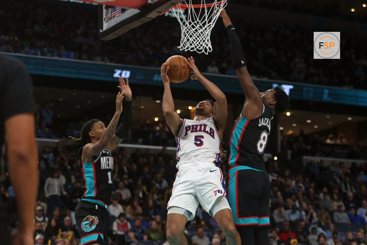 Dec 30, 2025; Memphis, Tennessee, USA; Philadelphia 76ers guard Quentin Grimes (5) shoots as Memphis Grizzlies guard Ja Morant (12) and Memphis Grizzlies forward/center Jaren Jackson Jr. (8) defend during the second quarter at FedExForum. Credit: Petre Thomas-Imagn Images