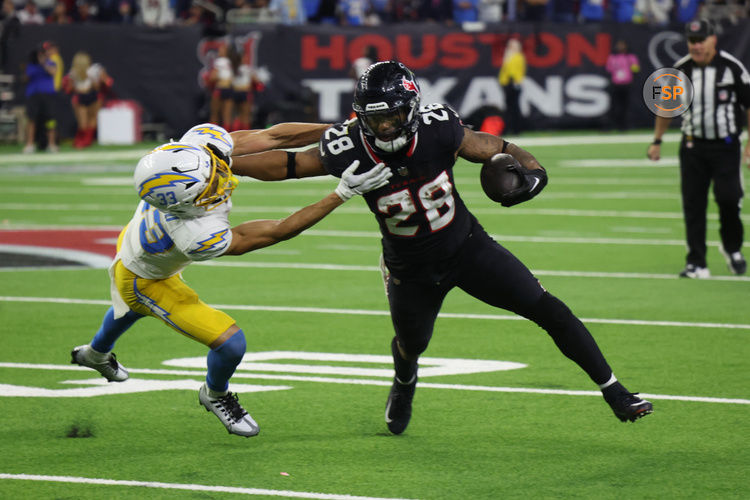 Jan 11, 2025; Houston, Texas, USA; -Los Angeles Chargers defensive back Deane Leonard (33) reaches for Houston Texans running back Joe Mixon (28) in the fourth quarter in an AFC wild card game at NRG Stadium. Credit: Thomas Shea-Imagn Images