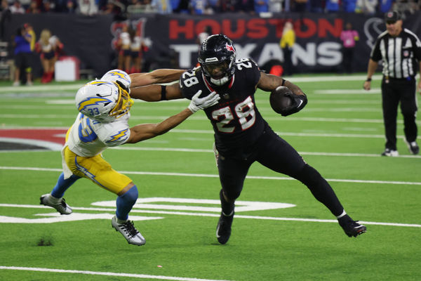 Jan 11, 2025; Houston, Texas, USA; -Los Angeles Chargers defensive back Deane Leonard (33) reaches for Houston Texans running back Joe Mixon (28) in the fourth quarter in an AFC wild card game at NRG Stadium. Mandatory Credit: Thomas Shea-Imagn Images