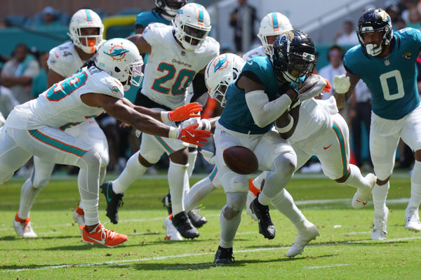 Sep 8, 2024; Miami Gardens, Florida, USA;  Miami Dolphins safety Jevon Holland (8) punches the ball away from Jacksonville Jaguars running back Travis Etienne Jr. (1) causing a fumble that was recovered by the Dolphins in the end zone during the third quarter at Hard Rock Stadium. Mandatory Credit: Jim Rassol-Imagn Images