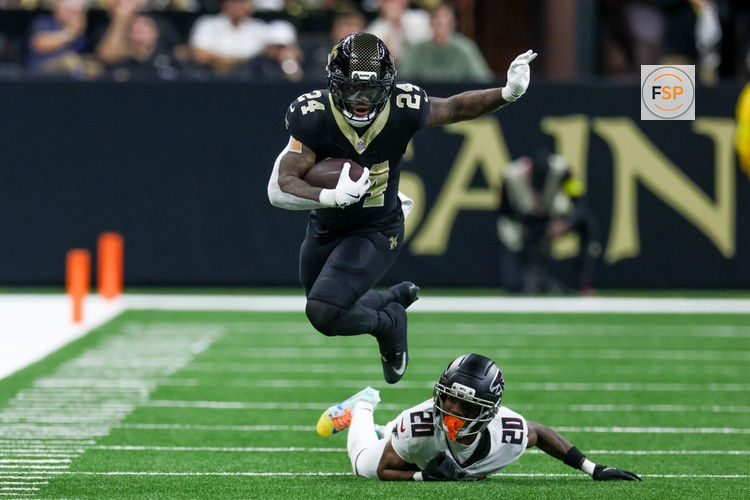 Nov 23, 2025; New Orleans, Louisiana, USA; New Orleans Saints running back Devin Neal (24) jumps over Atlanta Falcons cornerback Dee Alford (20) as he carries the ball during the second half at Caesars Superdome. Credit: Stephen Lew-Imagn Images