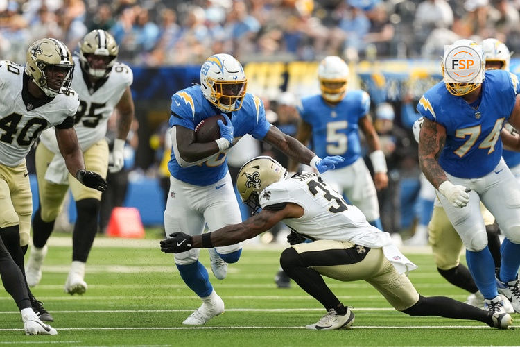 Aug 10, 2025; Inglewood, California, USA; Los Angeles Chargers running back Hassan Haskins (28) runs the ball and is tacked by New Orleans Saints safety Jonas Sanker (33) at SoFi Stadium. Credit: Jon Endow-Imagn Images
